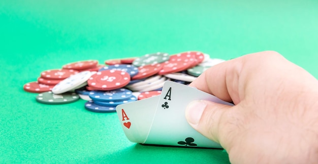 Männliche Hand zeigt ein Paar Asse auf dem grünen Pokertisch