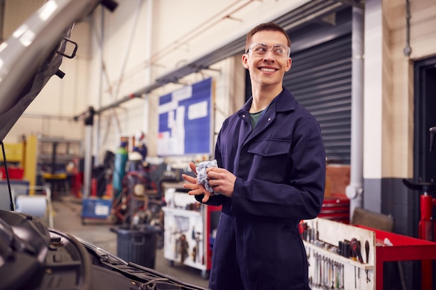 Männliche Kfz-Mechaniker wischen sich die Hände nach der Arbeit am Automotor in der Garage