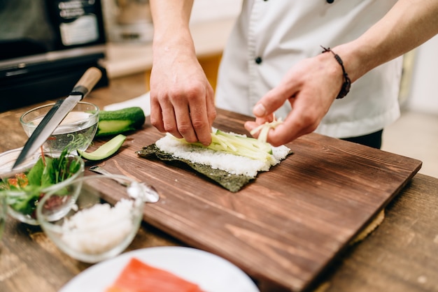 Männliche Kochhände, die Sushi-Rollen machen