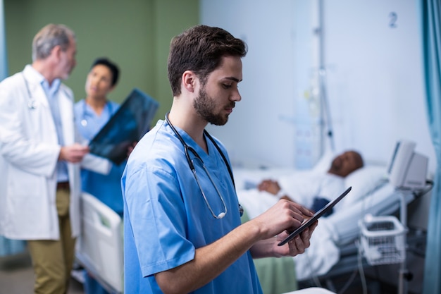 Männliche Krankenschwester mit digitaler Tablette in der Station