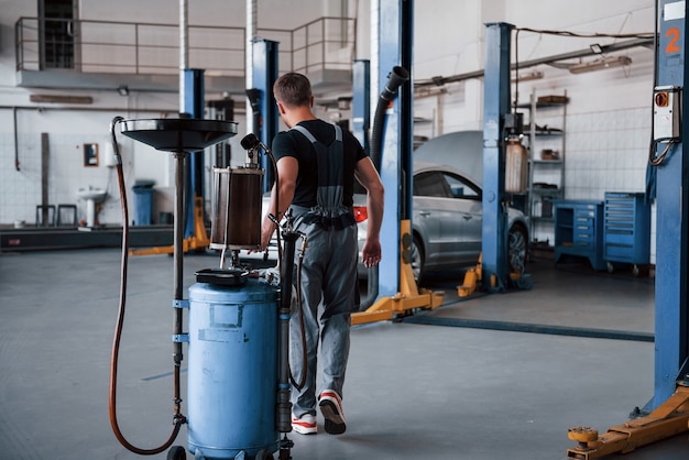 Männliche Mechaniker verwenden spezielle Geräte, um kaputte Autos zu reparieren