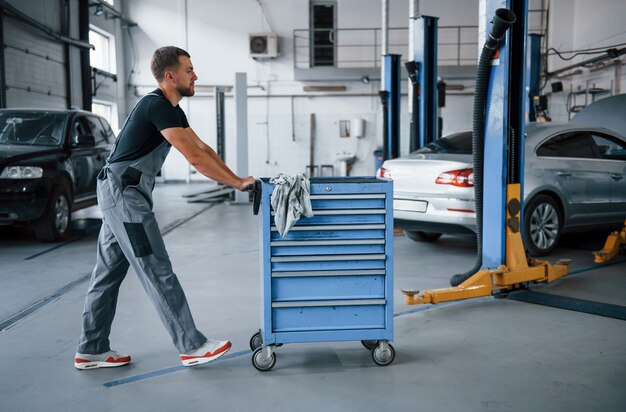 Männliche Mechaniker verwenden verschiedene Werkzeuge, um kaputte Autos in der Garage zu reparieren