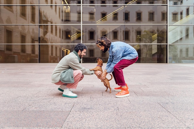 Männliche Paare, die mit ihrem verspielten kleinen Hund spielen