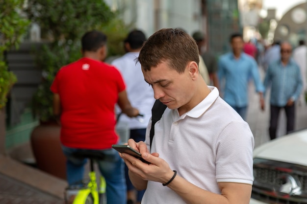 Männliche Touristen kommunizieren in sozialen Netzwerken auf einem Smartphone, während sie auf einer Straße im muslimischen Viertel der Stadt stehen