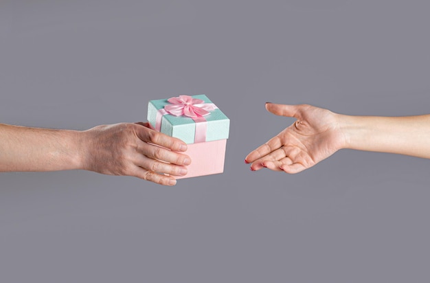 Männliche und weibliche Hände, die rosa Geschenkbox halten Mädchen gibt dem Menschen ein Geschenk Frau Hände halten Geschenk Geschenkbox in der Hand Überraschungs- und Feiertagskonzept Mannhände, die Valentinstaggeschenk halten