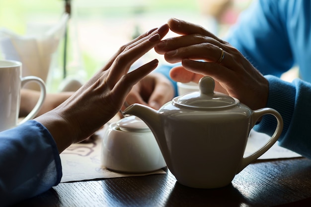 Männliche und weibliche Handflächen berühren sich in der Nähe eines Tisches in einem Café.