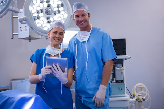 Männliche und weibliche Krankenschwester, die digitales Tablett im Operationssaal verwendet