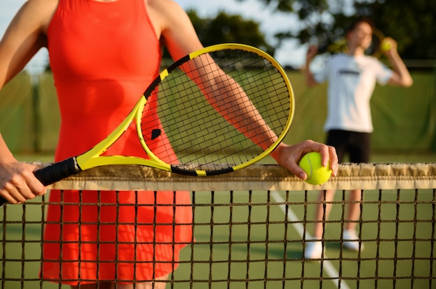 Männliche und weibliche Tennisspieler mit Schlägern, Training auf dem Außenplatz. Aktiver gesunder Lebensstil, Menschen spielen Sportspiel, Fitness-Training mit Schlägern