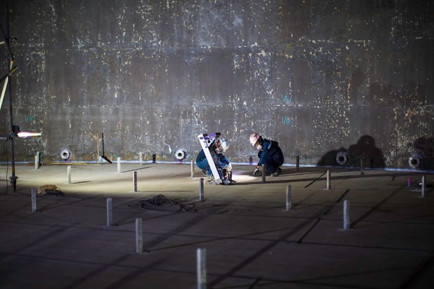 Männliche zwei Arbeiter Inspektionsboden Scan Tank externes Schwimmen der Rostwand verlieren Dicke Bodenplatte im Schachttank
