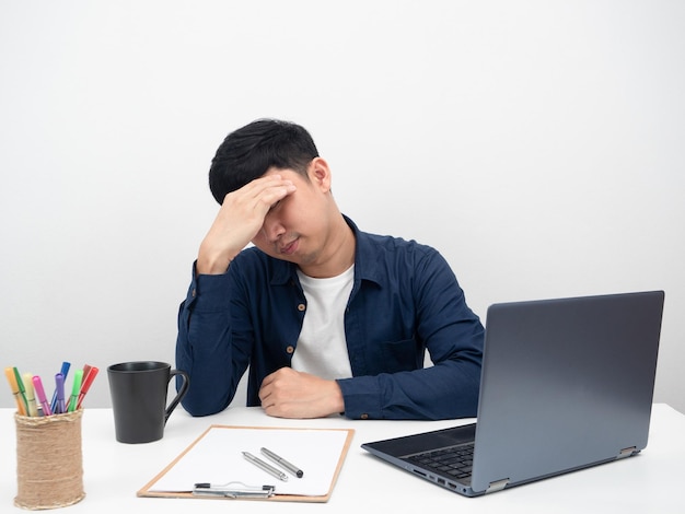 Männlicher Angestellter, der am Büroarbeitsplatz sitzt, fühlt Kopfschmerzen, Laptop auf dem Tisch
