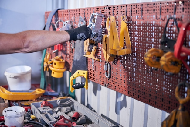 Männlicher Arbeiter, der Autoreparaturwerkzeug in der Garage greift