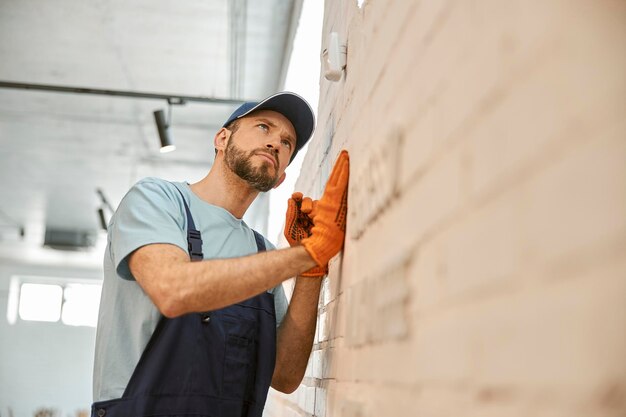 Männlicher Arbeiter, der die Überwachungskamera an der Wand überprüft