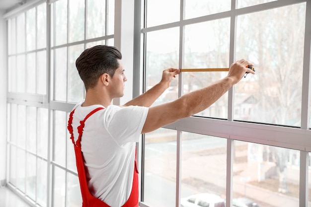 Männlicher Arbeiter, der Fenster in Wohnung installiert