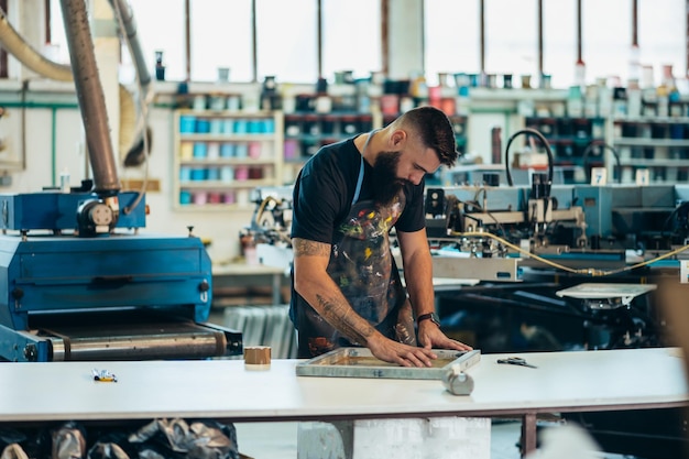 Männlicher Arbeiter, der Siebdruckfilm in einer Werkstatt vorbereitet