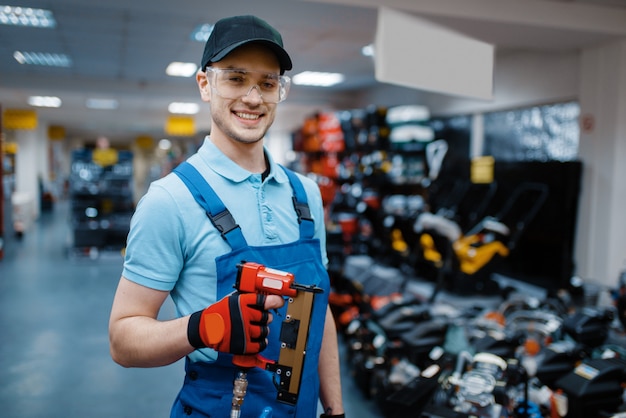 Männlicher Arbeiter hält pneumatischen Nagler im Werkzeugspeicher