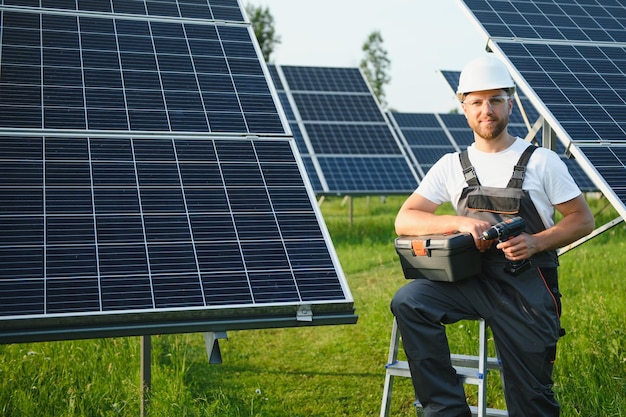 Männlicher Arbeiter in Uniform im Freien mit Solarbatterien an sonnigen Tagen