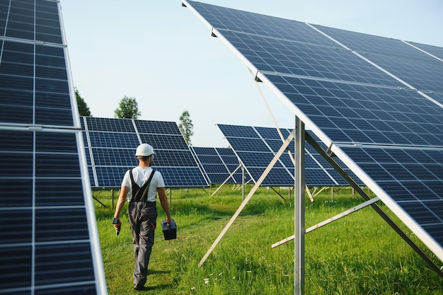 Männlicher Arbeiter in Uniform im Freien mit Solarbatterien an sonnigen Tagen