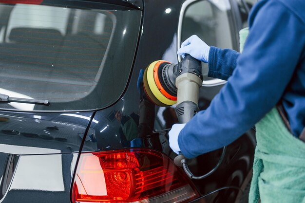 Männlicher Arbeiter in Uniform poliert neues modernes Auto Konzeption des Dienstes