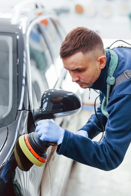 Männlicher Arbeiter in Uniform poliert neues modernes Auto Konzeption des Dienstes