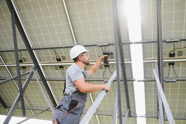 Männlicher Arbeiter mit Solarbatterien. Mann mit Schutzhelm. Installation einer eigenständigen Solaranlage