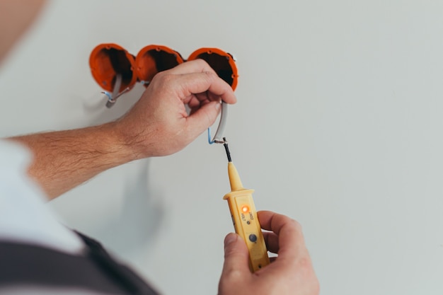 Männlicher Arbeiter professioneller Elektriker montiert nach der Reparatur eine Steckdose in der Wohnung, Nahaufnahme des Installateurs