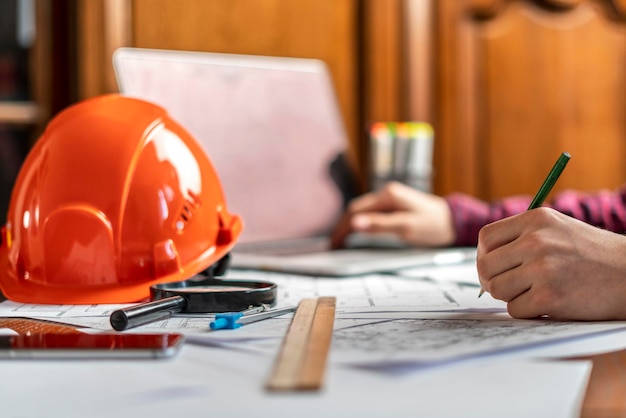 Männlicher Arbeiter unterschreibt Dokumente mit Helm auf einem Tisch b