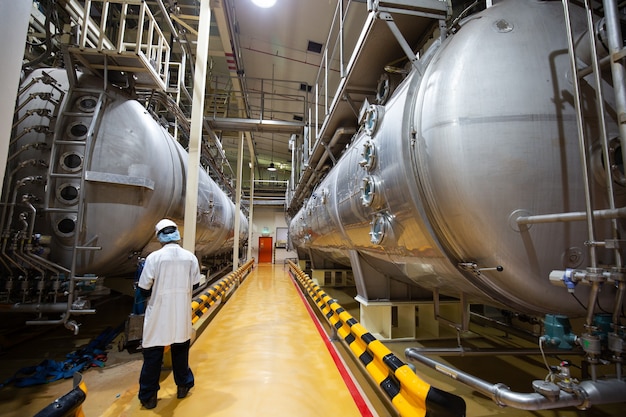 Männlicher Arbeitsinspektionsprozess Milchpulverkeller in der Fabrik mit horizontalen Edelstahltanks