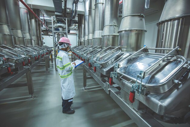 Männlicher Arbeitsinspektionsprozess-Pulverkeller in der Fabrik mit vertikalen Edelstahltanks