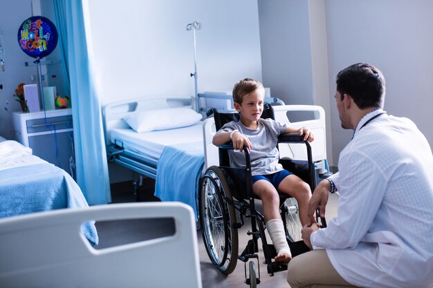 Männlicher Arzt, der mit dem Kinderpatienten in der Station interagiert