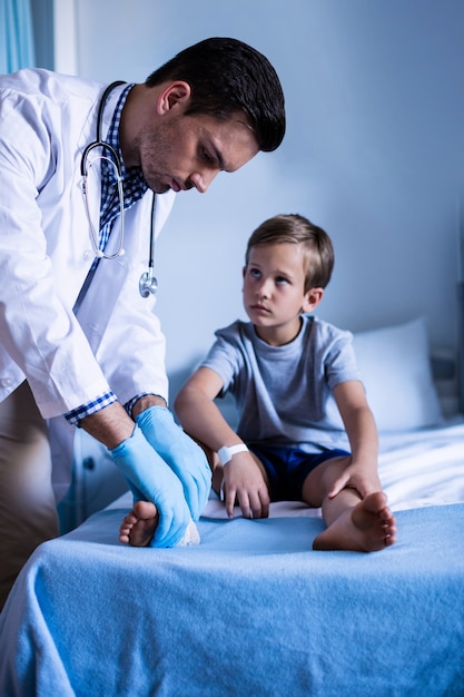 Männlicher Arzt, der Patientenbein untersucht