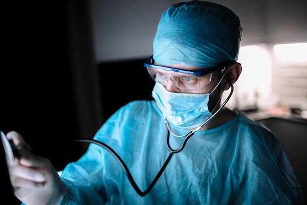 männlicher arzt in uniform und brille mit einem stethoskop in die lunge des patienten