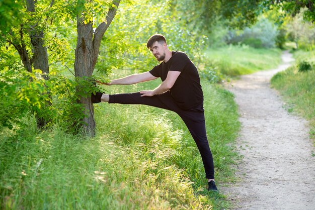 Männlicher Athlet, der Beinstreckung in der Natur tut