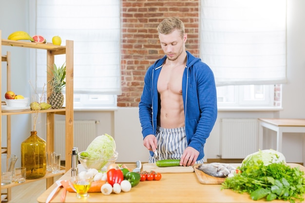 Männlicher Athlet, der gesundes Essen zu Hause in der Küche vorbereitet