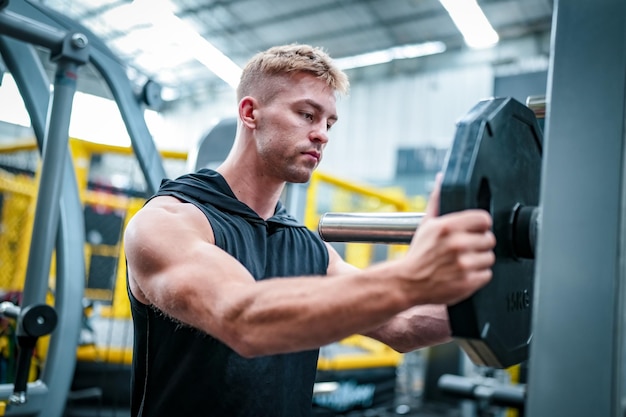 Männlicher Athlet, der im Fitnessstudio trainiert und Gewichte hebt, die Gelenke ziehen