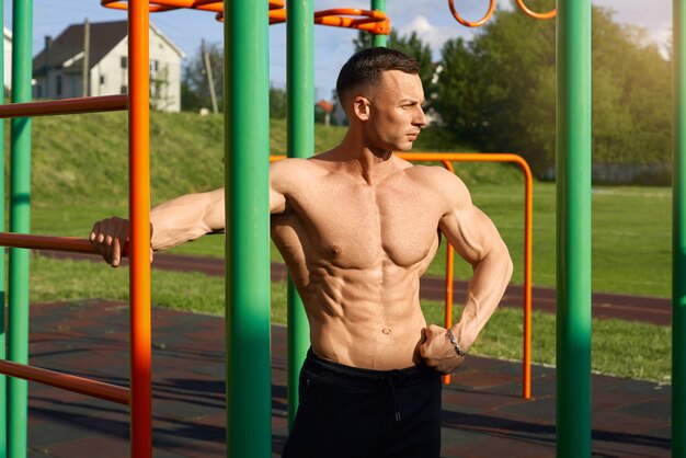 Foto männlicher athlet mit nacktem oberkörper postet auf dem sportplatz