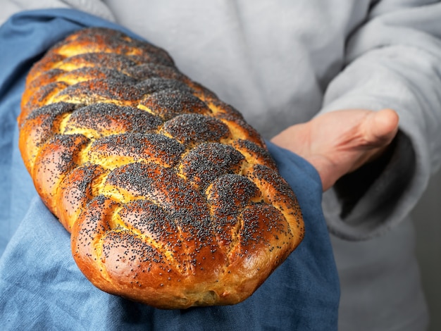 Männlicher Bäcker hält ein traditionelles süßes jüdisches Challa-Brot