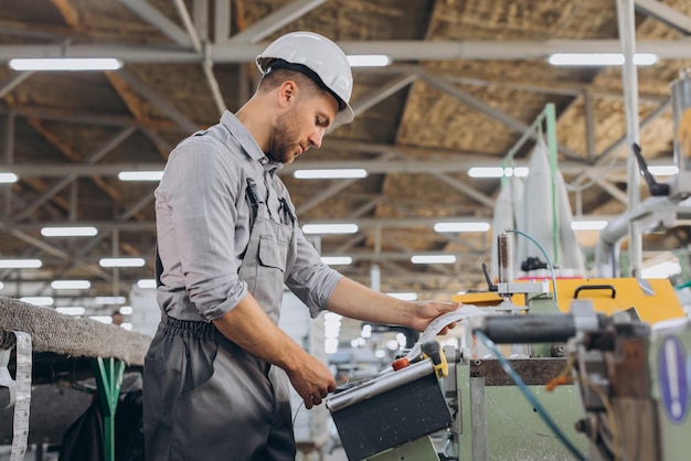 Männlicher bärtiger Fabrikarbeiter programmiert eine CNC-Fräsmaschine mit Kopierraum