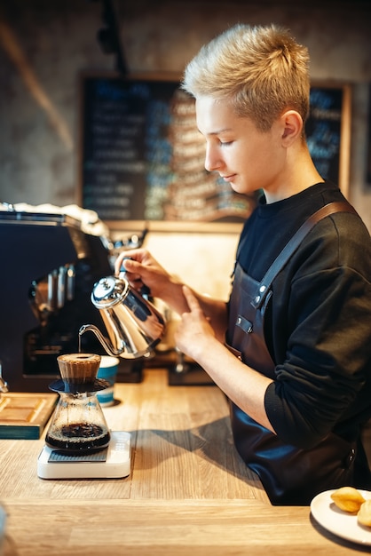 Männlicher Barista gießt kochendes Wasser in das Glas