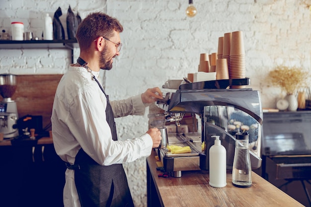 Männlicher Barista mit professioneller Kaffeemaschine im Café