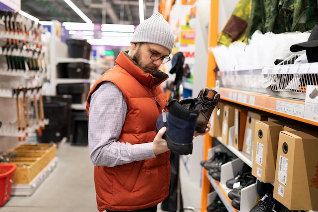 Männlicher Baumeister in einem Baumarkt, der neue Sicherheitsschuhe abholt