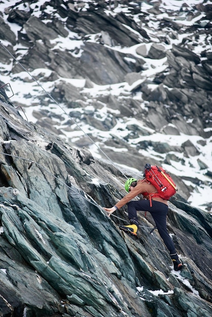 Männlicher Bergsteiger, der felsigen Berg klettert