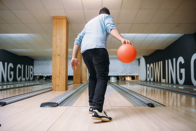 Männlicher Bowler, der auf Spur steht und mit Ball aufwirft