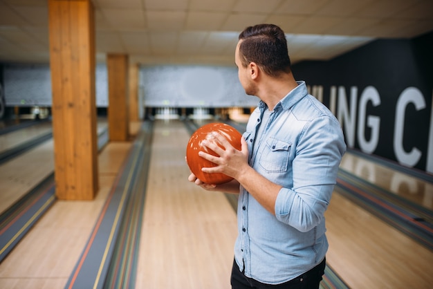 Männlicher Bowler, der auf Spur steht und mit Ball aufwirft