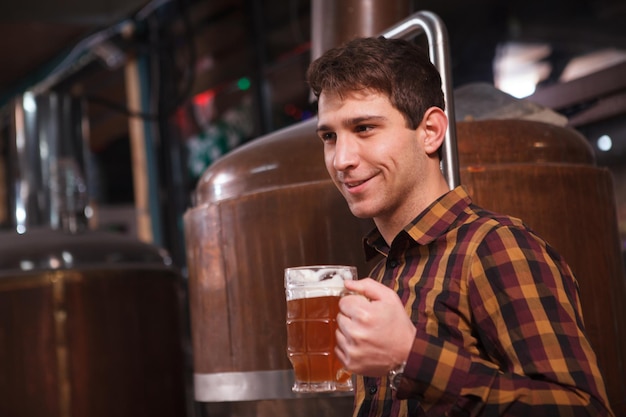 Männlicher Brauer genießt Bierverkostung in seiner Mikrobrauerei, Kopierraum