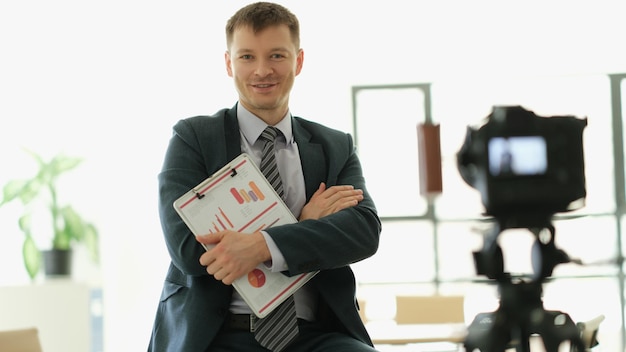 Männlicher Business-Coach steht mit Dokumenten in der Hand vor der Kamera