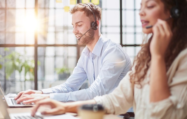 Foto männlicher callcenter-operator mit kopfhörern sitzt in einem modernen büro