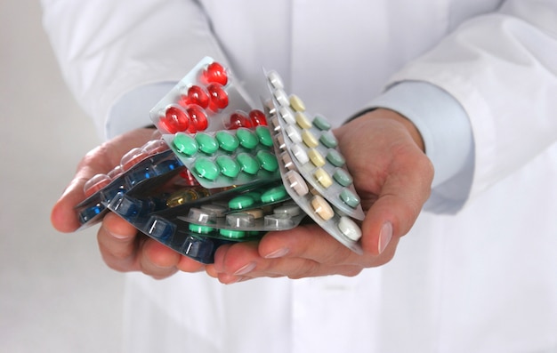 Foto männlicher doktor, der einen stapel vieler verschiedenen pillen hält
