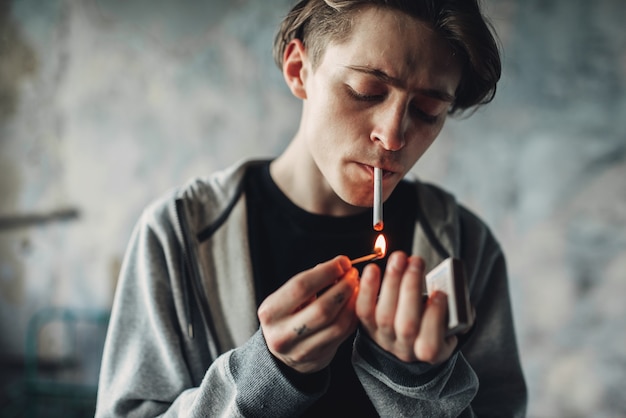Foto männlicher drogenabhängiger zündet sich eine zigarette an