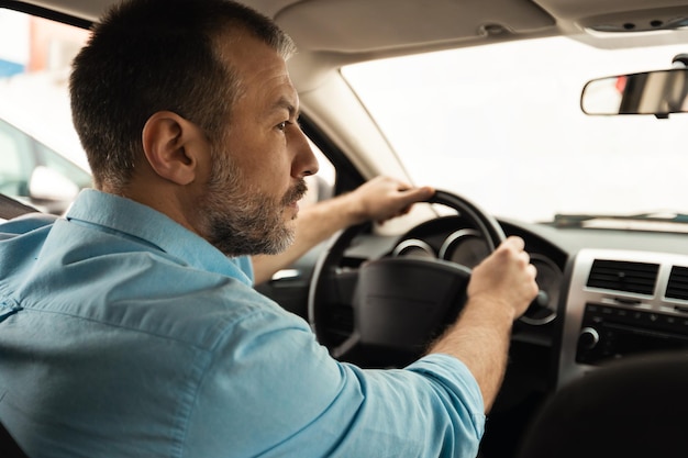 Männlicher Fahrer, der in der Rückansicht des Autos sitzt