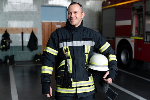 Männlicher Feuerwehrmann posiert mit Anzug und Helm